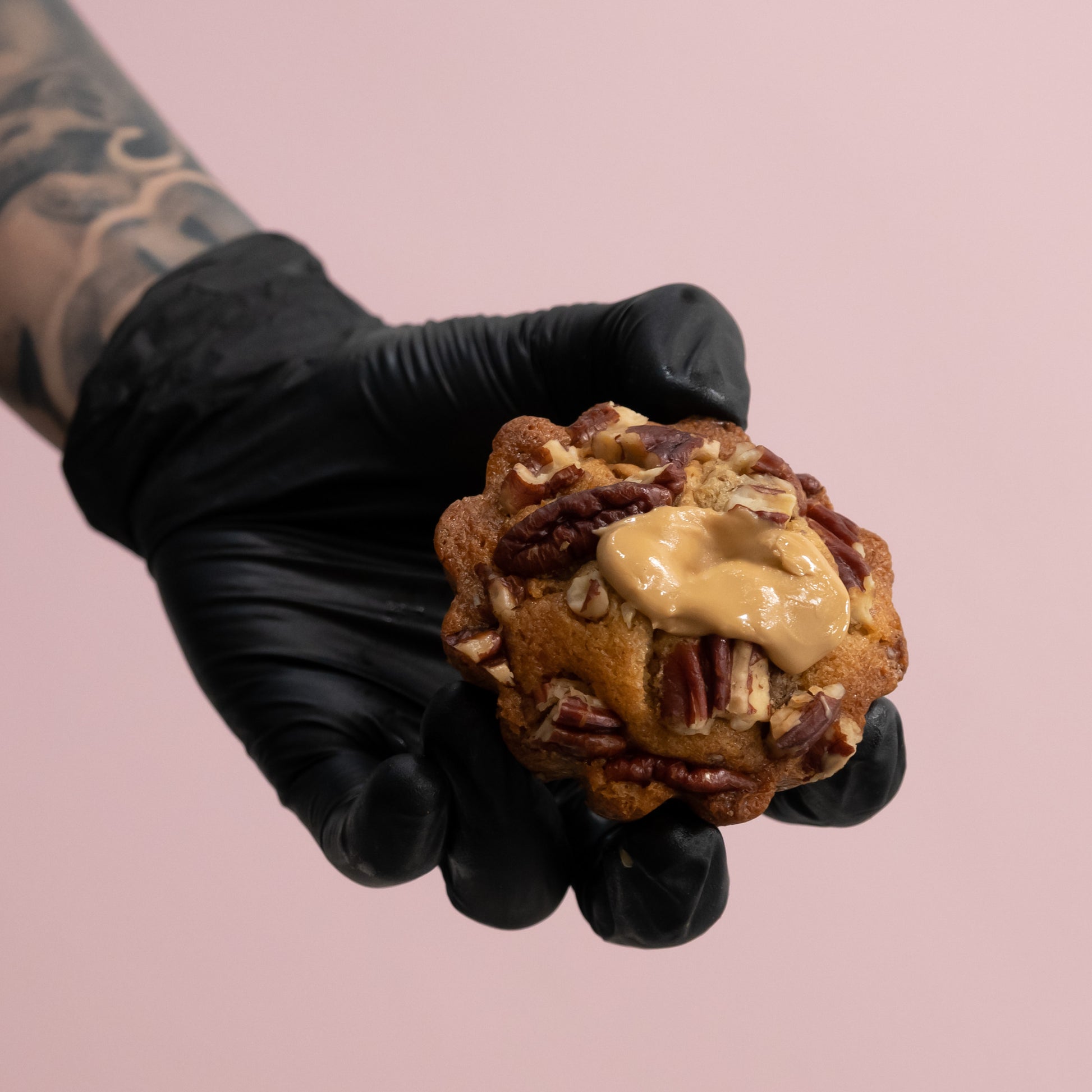 hand with black glove holding Mooi Patisserie blondie with pecan nuts and Dulcey Chocolate