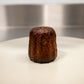 A side view of a canelé pastry, showing its dark, caramelized exterior and distinctive fluted shape.