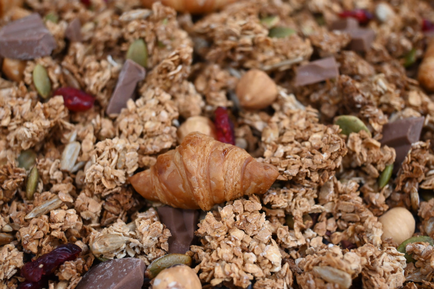 Close up of our granola with mini croissant, chocolate, nuts and seeds and dried cranberries.