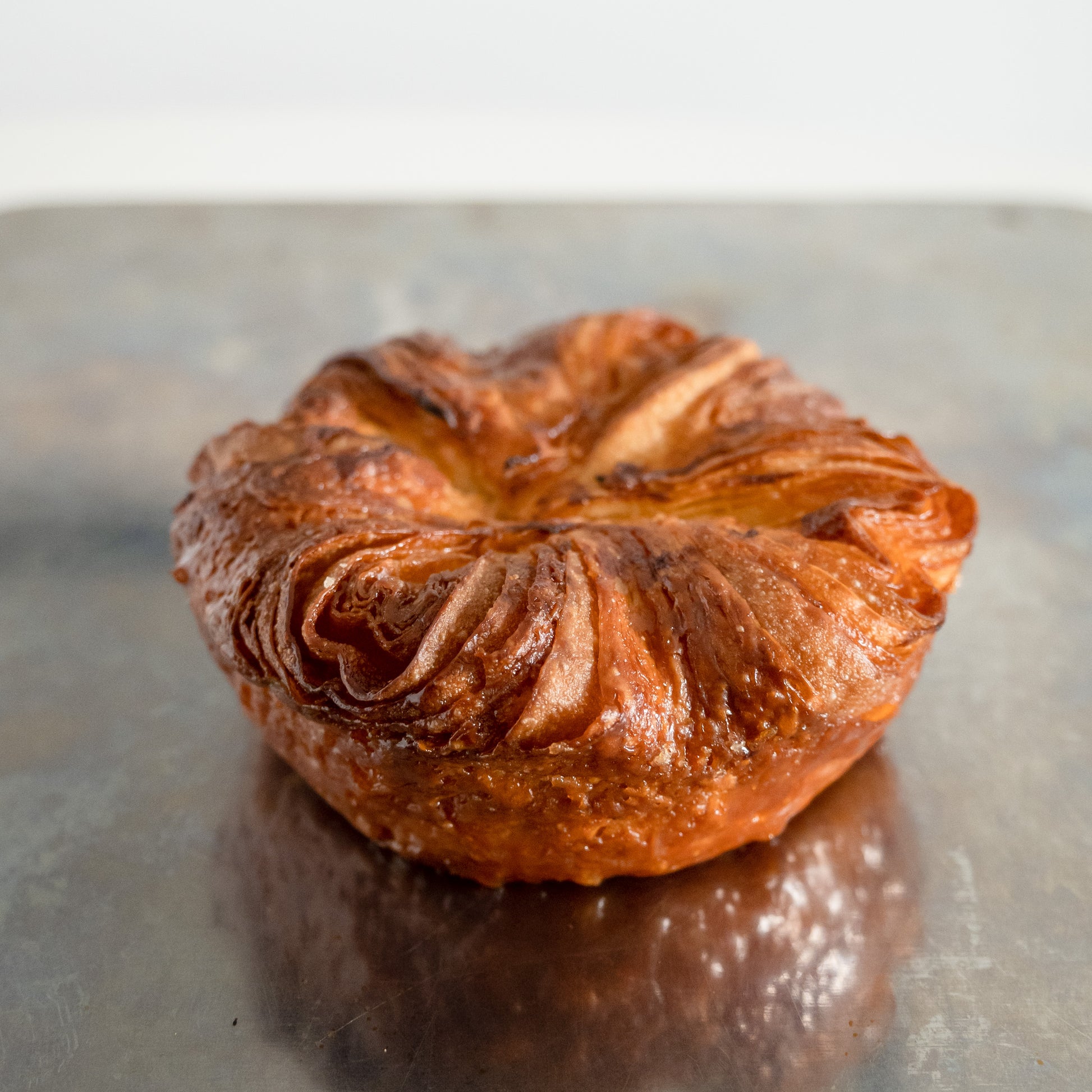 Kouign Amann - A traditional Breton pastry made with layers of buttery croissant dough, sugar, and a hint of sea salt, caramelized to perfection. The result is a crispy, flaky, and irresistibly buttery pastry with a slightly sweet, caramelized flavor.