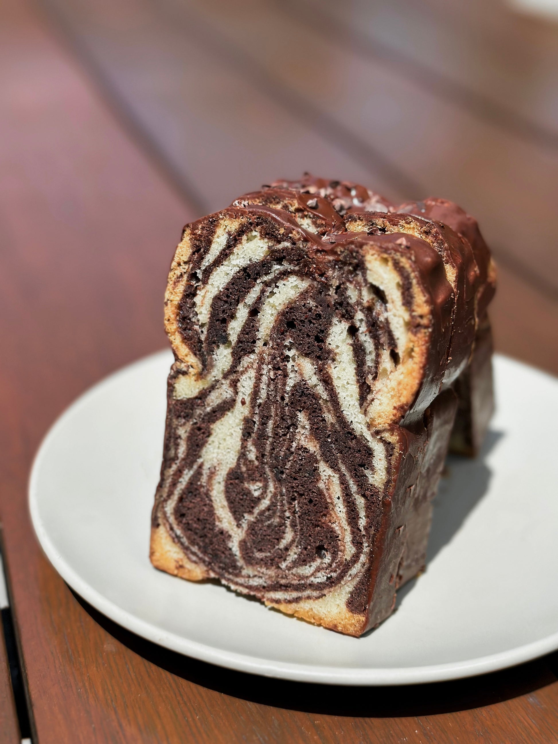 Slice of Marble Cake made with premium Valrhona cocoa powder and pure vanilla extract. The combination of moist vanilla and rich chocolate cake swirled together creates a delightful treat for any occasion.