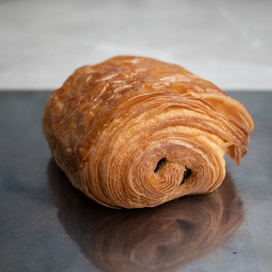 A freshly baked chocolate-filled pastry, with layers of flaky, buttery pastry and rich, dark chocolate in the center.
